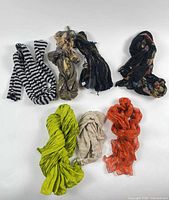 Seven scarves arranged on white background showing colours and patterns