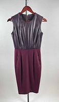 Full view of sleeveless leather and wool dress on hanger