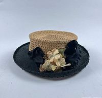 Front view of straw hat showing crown, black brim, floral decoration