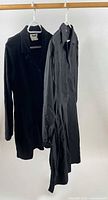 Two black cotton coat dresses hanging on hangers