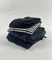 Stack of four folded pants showing different fabrics and patterns