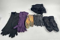 All five pairs of gloves/mittens plus neck warmer and headband displayed on white background
