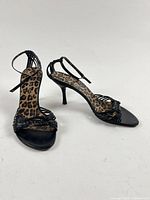 Full view of both shoes showing leopard insole, black strappy uppers and stiletto heels