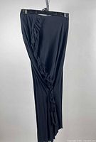 Full view of black skirt hanging, showing ruffle detail and length