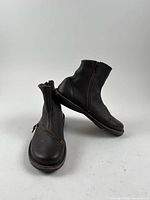 Pair of Trippen dark brown leather boots, side view showing vamp zipper detail and overall silhouette