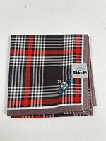 Folded tartan pocket square showing embroidery and brand tag