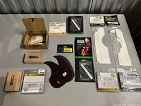 Overall lot showing all guitar parts, pickguards, Tusq packages, wooden blocks, hex key and box of nuts