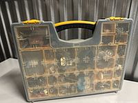 Front view of clear-lid organizer showing multiple compartments filled with assorted fasteners