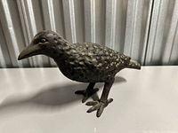 Side profile of cast iron crow showing textured surface and overall form