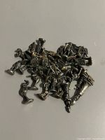 Pile of small silver-tone metal figurines on flat surface