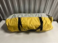 Yellow and gray tent carry bag with black handles