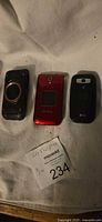 Three flip phones: Verizon rugged black, red Jitterbug, black LG