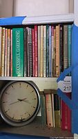 Two shelves showing full assortment of books and wall clock