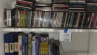 Shelf containing stacked horizontal and vertical CDs and lower row of movies