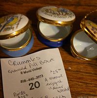 Three open Crummles enamel pill boxes showing interiors and lids