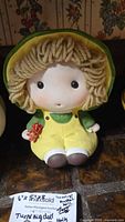 Front view of ceramic Holly Hobbie music box doll with yarn hair and flower