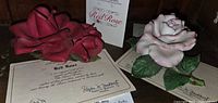 Both porcelain rose figurines with their COAs visible