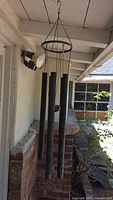 Full view of hanging pipe wind chimes on porch