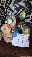 Group shot of cat figurine, two snow globes, painted eggs, stand