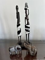 All four pieces grouped: two wood figures with bead skirts, two stone elephants