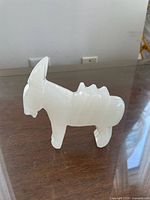 Right side profile of white marble donkey figurine on tabletop