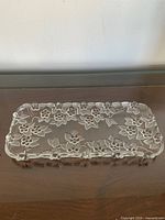Top view of clear pressed-glass tray showing holly & berries pattern