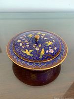 Top view of closed cloisonné lidded bowl showing bird and floral design and brass finial