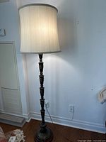 Full view of lit brass floor lamp with shade