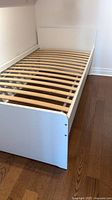 Overall view of white single bed frame showing slatted base and footboard