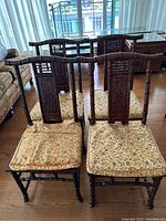 Front view of four hardwood faux-bamboo side chairs showing carved backs and upholstered seats