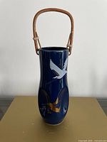 Front view of navy blue ceramic vase showing crane design and bamboo handle