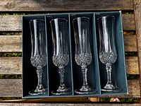 Open box showing four cut crystal champagne flutes in dividers