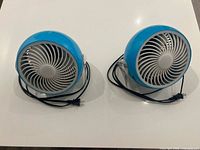 Front view of both blue 6" table fans with cords