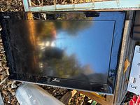 Front view of Sharp 32" Aquos TV leaning upright outdoors