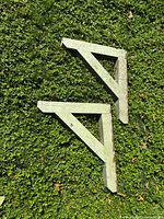 Pair of wooden triangular corbels on grass