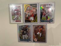 Group shot of the five football trading cards in sleeves