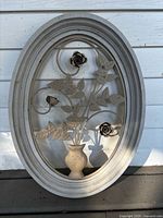 Front of oval wall art showing metal floral design