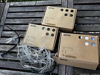 Three IKEA SKINA boxes with dragonfly string lights and one loose string displayed