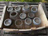 Cardboard box containing clear glass mason jars with lids