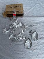 Cardboard box labeled glass drops with several teardrop chandelier prisms visible