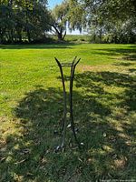 Full view of tall metal plant stand upright on lawn
