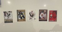 Five hockey trading cards laid out horizontally on white surface