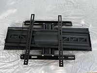 Front view of complete black metal TV wall mount showing back plate, adjustable arms and two vertical VESA rails