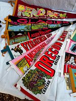 Stack of large pennants showing Reno, Glacier, Lassen, Virginia City, Anchorage, Oregon Caves graphics
