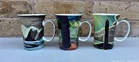 Front view of three McIntosh art mugs