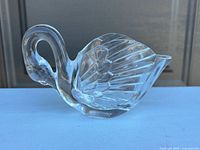 Left profile of clear glass swan creamer showing handle and wing detail