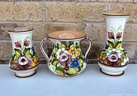 Front view of three Castelli vases showing shapes and floral decoration