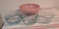 All four bowls grouped: three patterned clear Pyrex and one pink Hazel Atlas