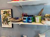 Shelf with poster, paint jars, basket of matchbooks, lighter, tealight tin