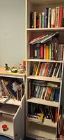 Full view of tall white bookcase and lower cabinet filled with books